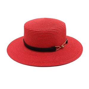 Close-up of a red woven straw boater hat with a black leather band and gold buckle detail