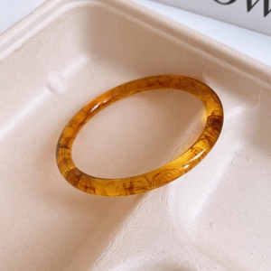 Close-up of an amber resin round bangle with tortoise texture in a neutral pulp tray