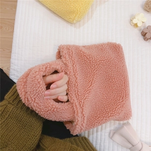 Détail d'un mini sac à main en polaire rose avec texture douce et poignée chic