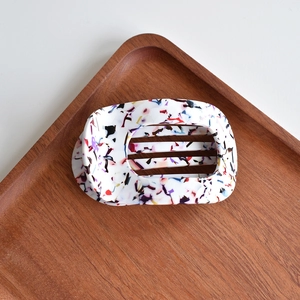 Close-up of elegant acetate hair claw clip with colorful terrazzo pattern and hollow design