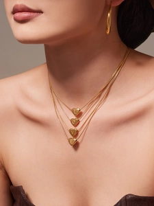 Dettaglio di una collana dorata a quattro strati con cuori L-O-V-E indossata da una modella