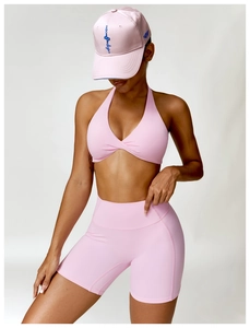 Detailed view of pink three-piece yoga set including sports bra, shorts and baseball cap