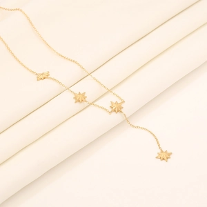 Detail view of golden star pendant necklace arranged on a soft beige fabric background