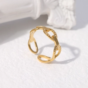 Vue macro d'une bague tressée dorée ajustable sur une surface blanche texturée