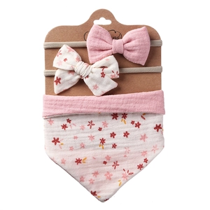 Detailed set of floral cotton baby bib and matching bow headbands on display card
