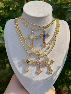 Detailed view of luxury cross pendants with colorful gemstones and pearls on gold bead chains