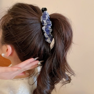 Détail de la pince à cheveux en tissu à carreaux bleu marine avec boules noires