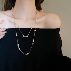 Détail du collier double rang doré élégant avec perles artificielles sur pull noir