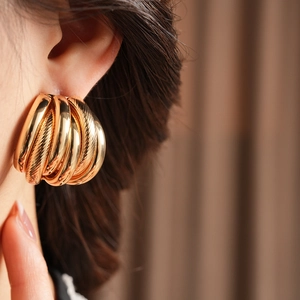 Close-up of elegant gold multi-layered textured hoop earrings worn on model ear