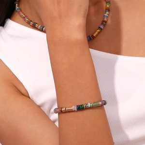 Détail d'un bracelet en perles dorées avec des écarteurs en pierres naturelles colorées