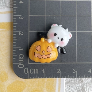 Macro shot of a cartoon ghost holding an orange pumpkin on a gray grid cutting mat