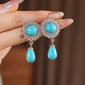 Close-up of vintage silver drop earrings with green turquoise stones and sparkling rhinestones