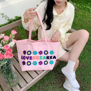Macro detail of floral embroidery and LOVESOZAKKA text on pink canvas tote bag