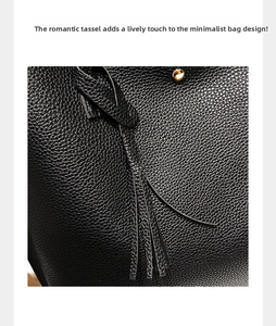 Close-up of black litchi pattern leather bag with tassel and gold metal buckle