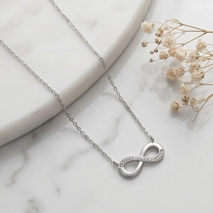 Detail of silver infinity necklace with sparkling rhinestones on marble stone