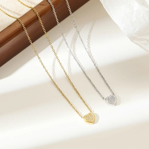 Elegant gold and silver heart necklaces with sparkling zircons on textured fabric