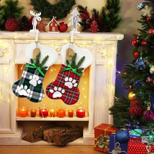 Detail of bone-shaped plaid Christmas stockings with pine cones on a cozy fireplace