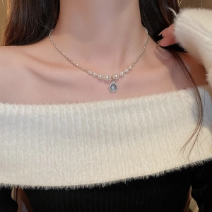 Close-up of pearl drop necklace with blue zircon pendant on a model's neck