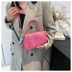 Fashionable magenta crossbody bag with gold hardware shown on a model in an oversized blazer