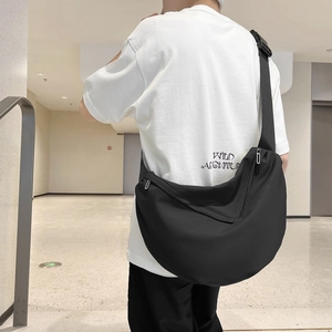 Black minimalist large capacity crescent messenger bag worn by male model in mall