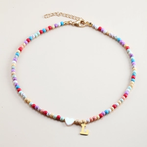 Detail of colorful beaded necklace with white heart charm and gold initial L pendant