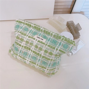 Close-up of green and white tweed makeup bag featuring a simple wish woven label