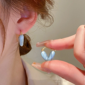 Boucles d'oreilles cœur dorées style français avec émail marbré bleu clair sur modèle