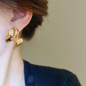 Close-up of a model wearing high-polish gold-plated C-shaped chunky twisted hoop earrings