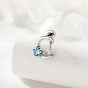 Silver crescent moon earring with blue star and clear teardrop zircon on a white pedestal