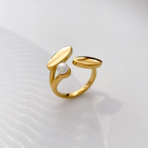 Detail of a gold pea-shaped crossover ring featuring a freshwater pearl and polished finish