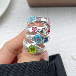 Detailed macro of four chunky silver Y2K rings set with vibrant colorful gemstones