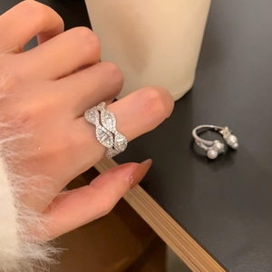 Nahaufnahme eines zweilagigen Zirkonia-Rings und eines Perlenrings auf einem Tisch