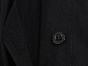 Close-up of black poplin shirt detailing a matching four-hole button and fabric texture
