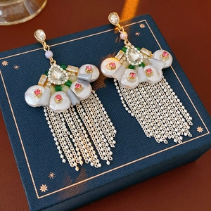 Detail of vintage fan-shaped earrings with pearls and tassels on a luxury blue jewelry box