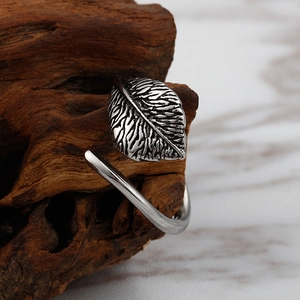 Macro shot of a silver leaf ring with detailed texture on a rustic wood block