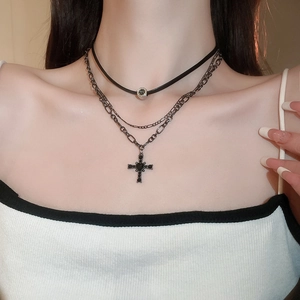 Dettaglio di una collana multistrato nera con croce di strass indossata dal modello