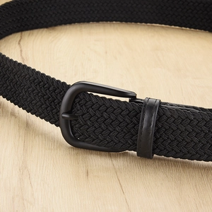 Elastic black woven belt with matte black metal buckle on a light wood background