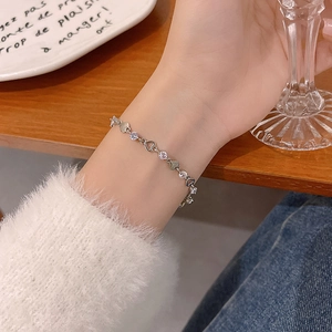 Dettaglio di un bracciale a cuore in argento con zirconi indossato al polso raffinato