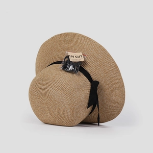 Close-up of beige woven straw sun hat with black ribbon and UV protection tag