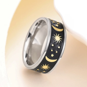 Detailed close-up of a silver ring featuring black band with gold sun, moon, and star patterns