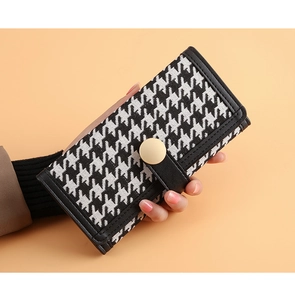 Detailed view of women long houndstooth wallet featuring a beige round button closure