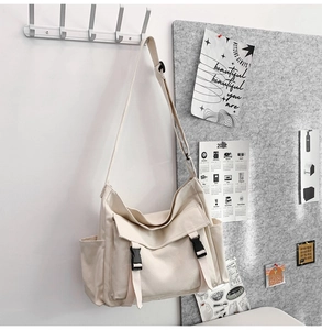 Détail du sac bandoulière en toile blanc cassé avec sangle réglable et boucle sur crochet