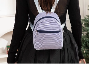Back view of a mini blue and white striped seersucker backpack worn by a person