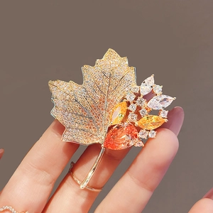Elegant gold maple leaf brooch with orange crystals and sparkling pear-shaped gems