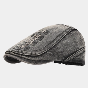 Close-up of washed denim texture and distressed embroidery on a vintage grey flat cap