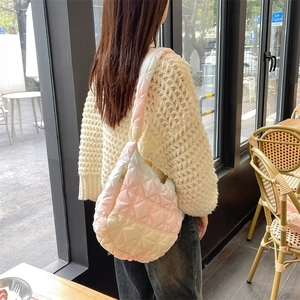Detailed view of pink gradient quilted cloud bag on shoulder with plush puffer strap texture