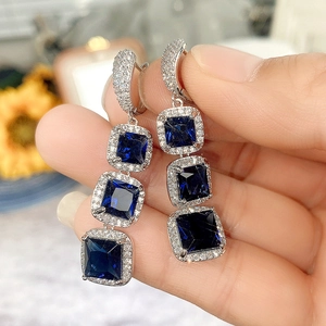 Macro view of long drop earrings with blue square-cut cubic zirconia and silver plating