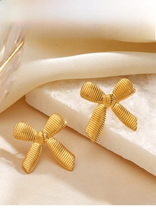 Macro detail of 18K gold plated bow earrings featuring elegant brushed metal texture