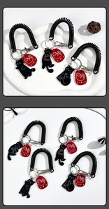 Detail of black cat acrylic keychains with spring coil lanyard and metal clasp hooks