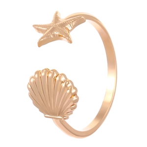 Elegante brazalete abierto dorado con diseño de estrella de mar y concha en metal pulido